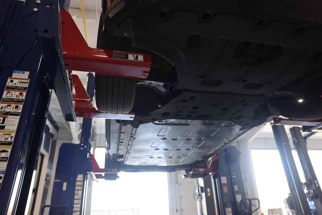 Technician working under a vehicle raised on CLHM mobile columns